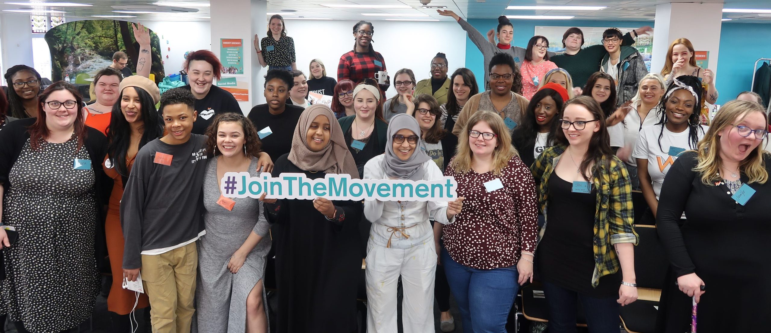 A big group of young women holding a sign that says #JoinTheMovement